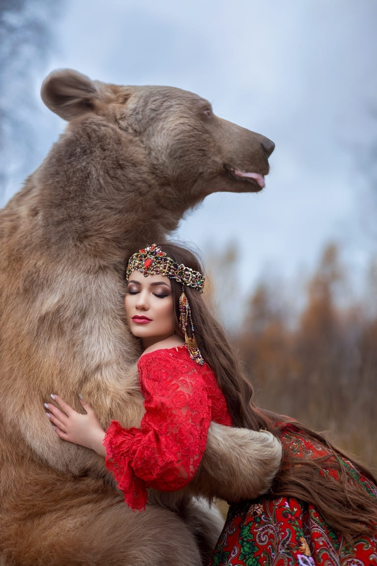 Девушка в красном сарафане с медведем среди деревьев