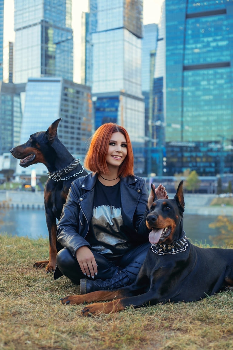 Искренняя улыбка женщины и дружелюбный доберман в парке